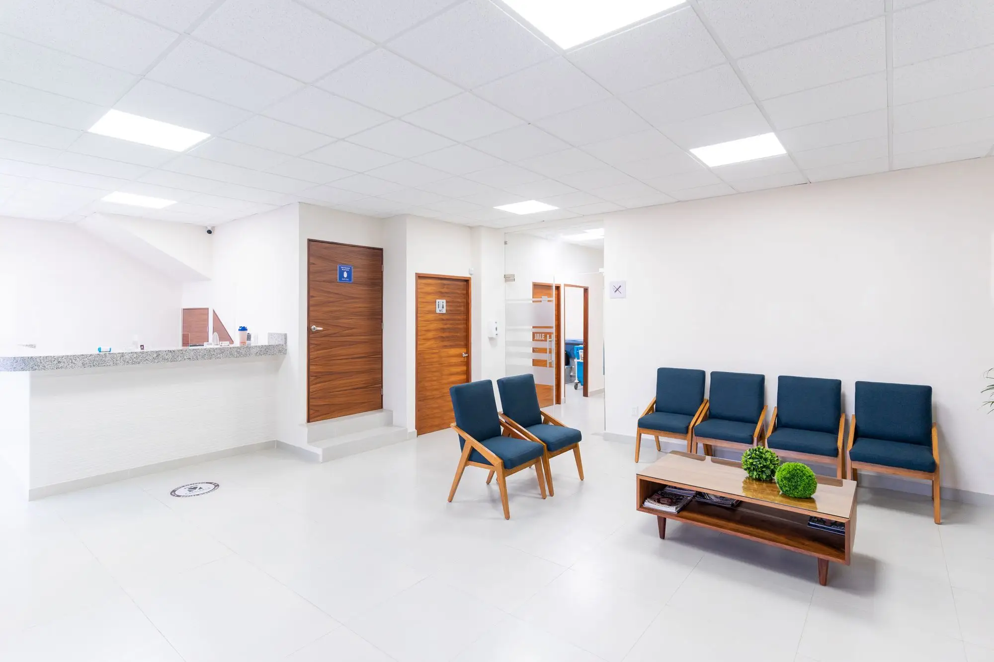 Recepção e sala de espera de uma clínica, com poltronas azuis